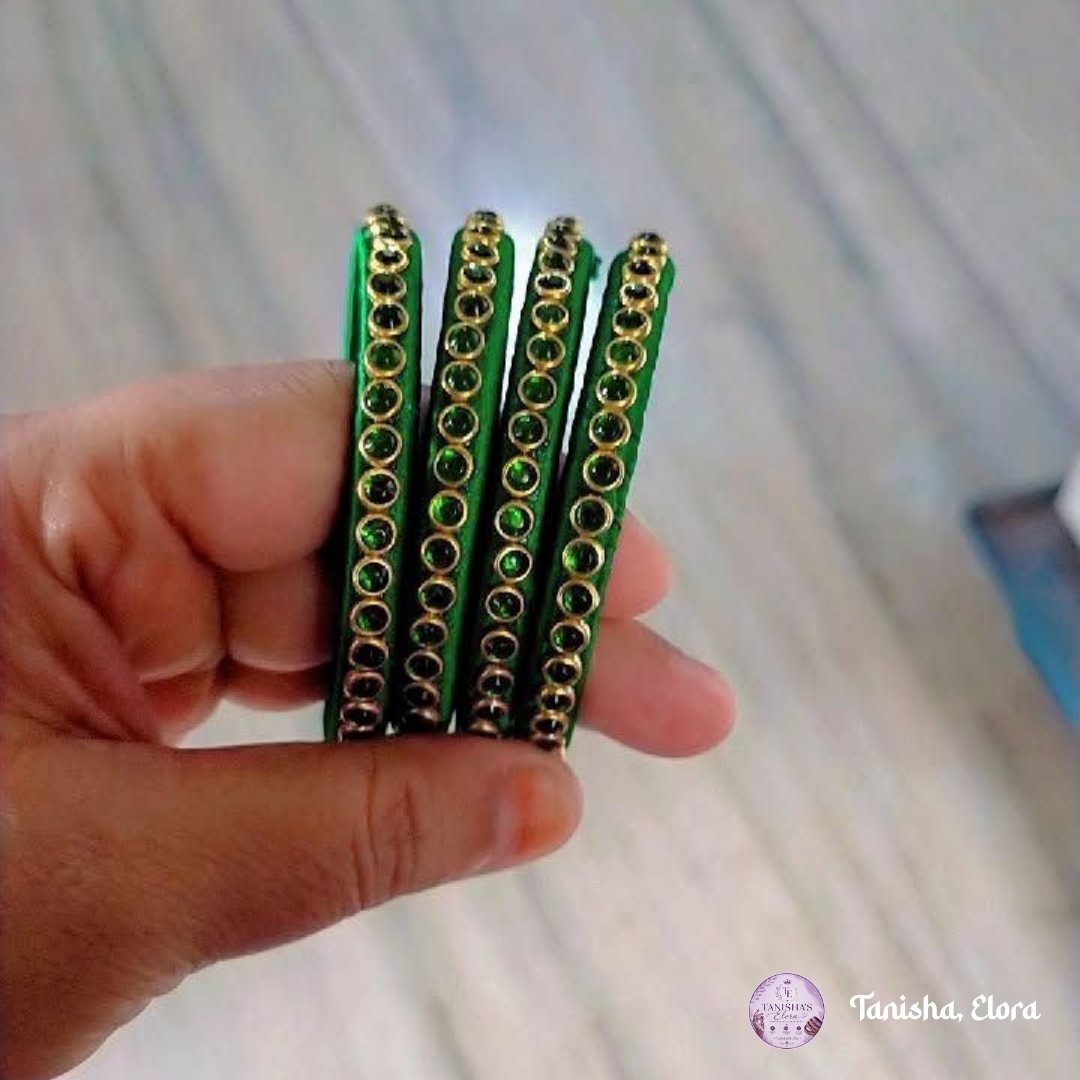 Hand holding solid emerald green Churi rods with gold-set stones
