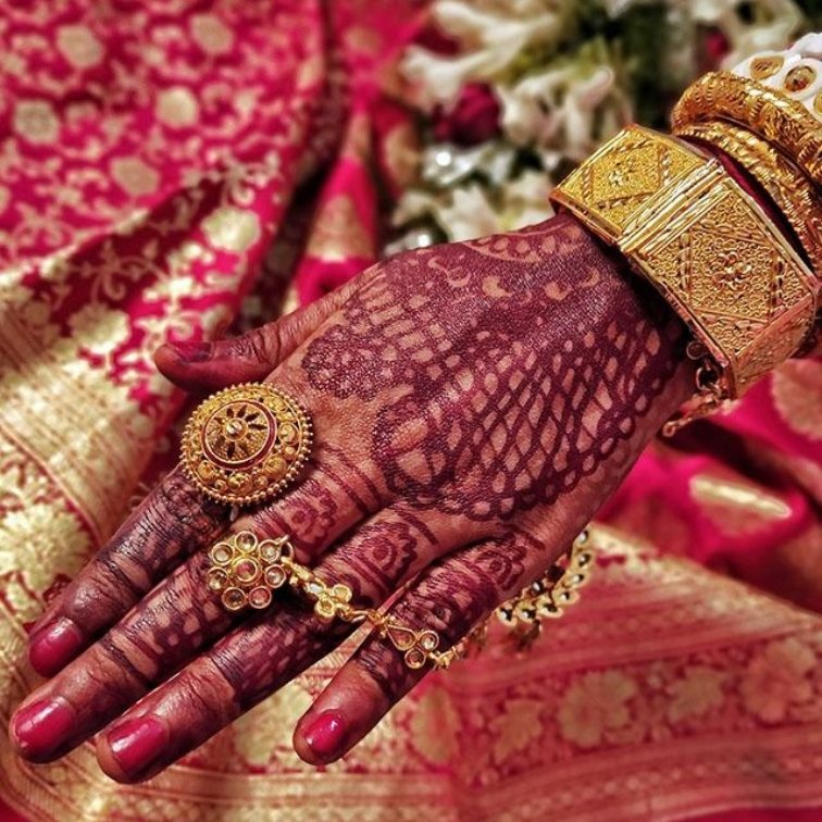 Mehendi-decorated palm against a pink silk saree